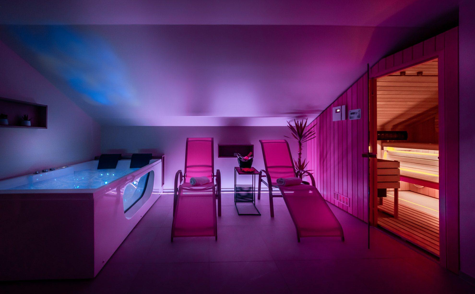 Wellness S-Center v rožnati ambientalni svetlobi — masažna kad, ležalnika in osvetljena savna