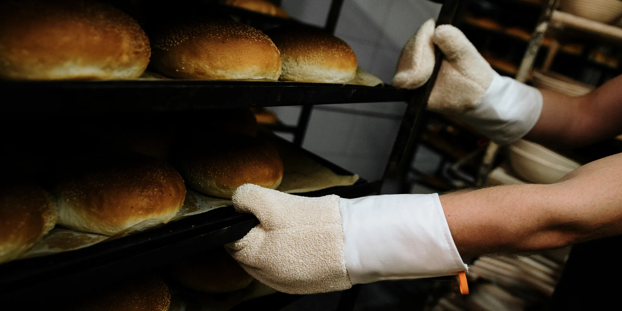 Roke v pekarskih rokavicah ob vozičku s svežim kruhom